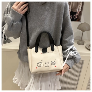 Détail d'un sac bandoulière beige avec des motifs d'ours mignons sur une texture raffinée