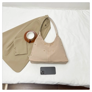 Détail du sac bandoulière en daim beige avec rivets dorés et coutures modernes