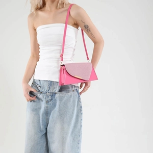 Sac bandoulière rose en patchwork avec détails dorés porté par un mannequin