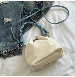 Detail of white PU bucket bag with blue woven handle and gold-tone hardware