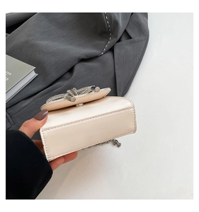 Vue détaillée du mini sac en cuir beige avec boucle strass et bandoulière chaîne