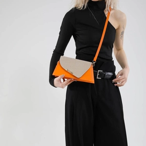 Sac bandoulière géométrique chic orange et beige avec texture paille porté par mannequin