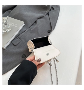 Détail du mini sac bandoulière crème avec chaîne argentée et fermeture magnétique