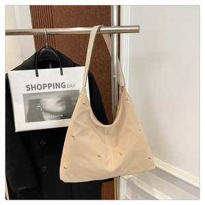 Vue détaillée du sac hobo beige avec des clous dorés et une bandoulière unique