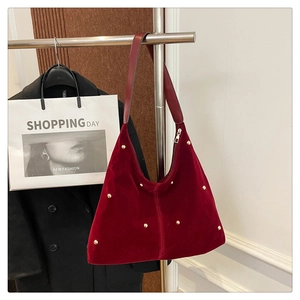 Détail du sac hobo en velours rouge foncé avec clous dorés et large bandoulière