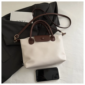 Détail du sac cabas en cuir grainé bicolore avec un téléphone pour comparer la taille