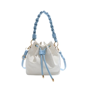 White leather bucket bag with blue woven handle and adjustable crossbody strap
