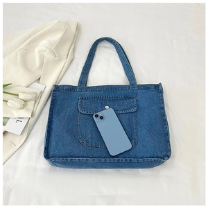 Detail of blue denim tote bag showing reinforced stitching and a metal button pocket