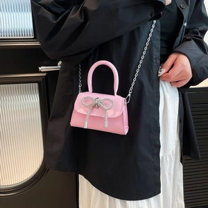 Mini sac à main rose en cuir verni avec nœud en strass et chaîne sur mannequin