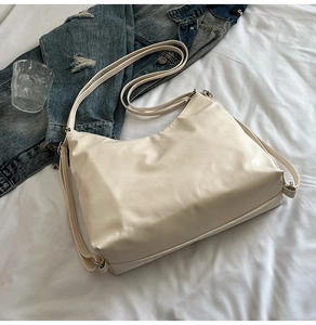 Minimalist beige tote bag styled with denim jacket and glass on white textured fabric