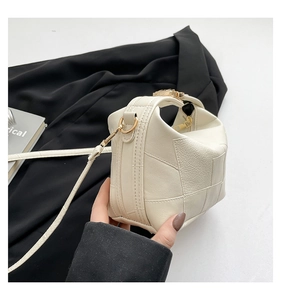 Close-up of off-white crossbody bag featuring woven texture and gold hardware details