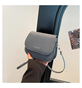 Detail of gray-blue tweed saddle bag with Fashion Trend logo held in hand