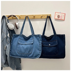 Detail of light and dark blue denim tote bags with large front button pockets