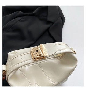 Detail of cream leather handbag showing gold metal flip lock and neat stitching on top
