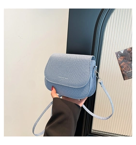 Detail of light blue saddle bag with woven texture and adjustable shoulder strap