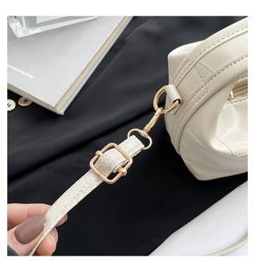 Close-up of golden hardware and crocodile pattern texture on beige shoulder bag