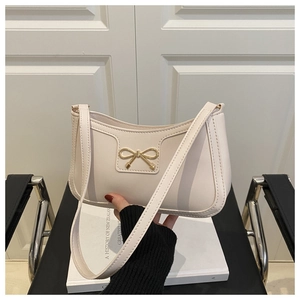 Close-up of off-white leather bag with a distinctive golden bow metal buckle detail