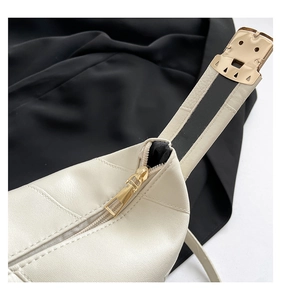Close-up of golden zipper hardware and leather texture on a beige shoulder bag