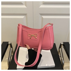 Detail of pink shoulder bag with gold metal bow and refined stitching craftsmanship