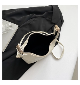 Detail of cream shoulder bag showing spacious interior and gold metal hardware adjustment
