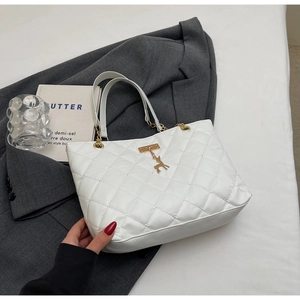Detail of white quilted tote bag featuring golden deer charm and chain leather handles