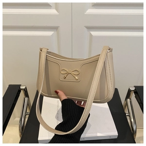 Detail view of beige matte leather shoulder bag featuring a gold bow metal buckle