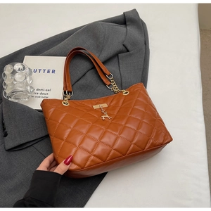 Detail view of brown quilted tote bag with golden deer charm and metal chain strap