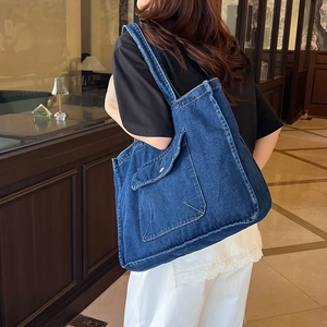 Minimalist deep blue denim tote bag with functional pockets worn by a model in a cafe
