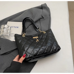 Detailed shot of a black quilted tote bag with gold chain strap and deer pendant detail