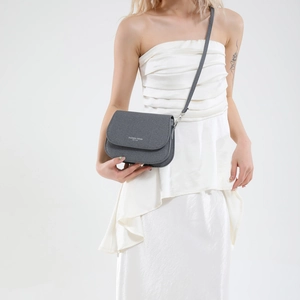 Minimalist grey textured leather saddle bag shown on a model in a studio setting