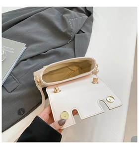 Detail of cream crossbody bag interior with dual magnetic snaps and gold hardware