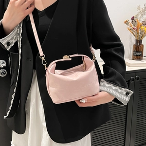 Pink quilted crossbody handbag with gold hardware worn by a model in a modern setting