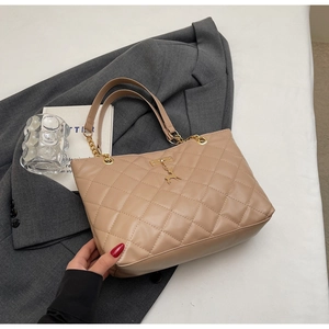 Close-up of beige quilted tote bag featuring gold chain strap and deer charm detail