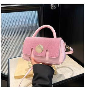 Detail of pink crossbody bag featuring striped fabric flap and gold round metal buckle