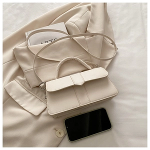 Detail of cream leather handbag with geometric flap on minimalist office blazer
