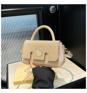 Close-up of elegant beige handbag featuring woven texture flap and golden round buckle
