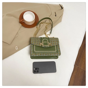 Detail of green tweed crossbody bag with gold buckle on a beige blazer background