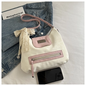 Detail of a contrast color tote bag featuring a cream body with pink flap and lace bow charm