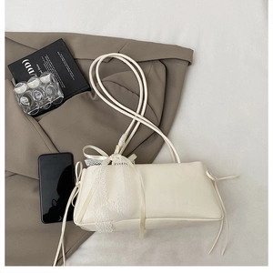 Detail of cream white rectangular bag with lace bow decoration on textured PU leather