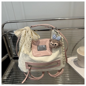 Detail of canvas backpack with pink leather trim and cartoon plush character charm