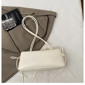 Chic beige rectangular baguette bag with delicate side bows and slim shoulder strap