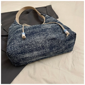 Detail einer blauen Denim-Tasche mit weißen Punkten und Perlen-Kordelzug-Details