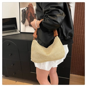 Detail der beige gewebten Strohschultertasche mit braunem Ledergriff in Lifestyle-Umgebung