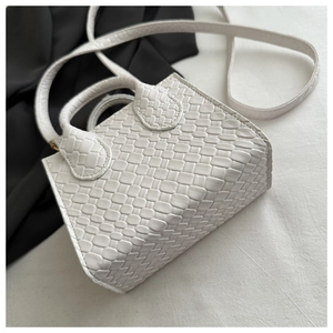 Detail view of woven leather texture on a white minimalist crossbody tote handbag