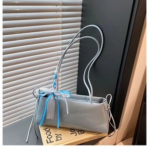 Detail of light blue patent leather bag featuring side drawstring and lace bow
