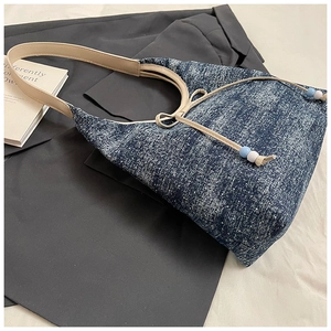 Detailaufnahme der blauen Textur-Tasche mit beigem Riemen und Schleifendetail