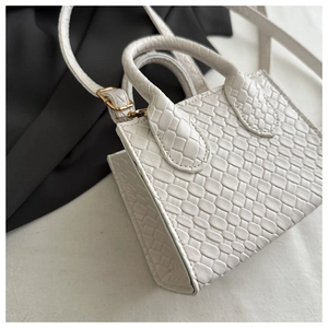 Detail of white mini crossbody bag featuring a textured woven checkerboard pattern