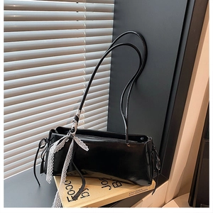Detail of glossy black shoulder bag with lace bow on vintage book by window