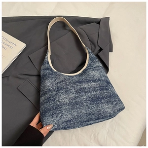 Nahaufnahme der blauen Denim-Tasche mit weißen Lederriemen auf weißer Bettwäsche