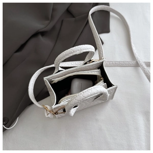 Detailed view of white crocodile embossed mini handbag showing inner storage capacity